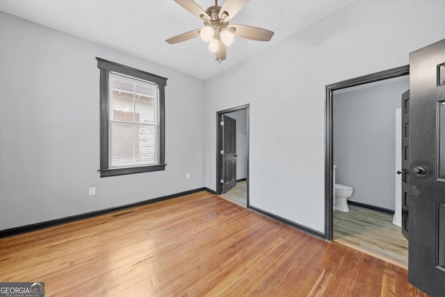 unfurnished bedroom featuring ceiling fan, ensuite bath, hardwood / wood-style floors, and a closet