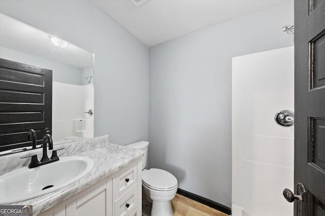 bathroom featuring walk in shower, vanity, and toilet