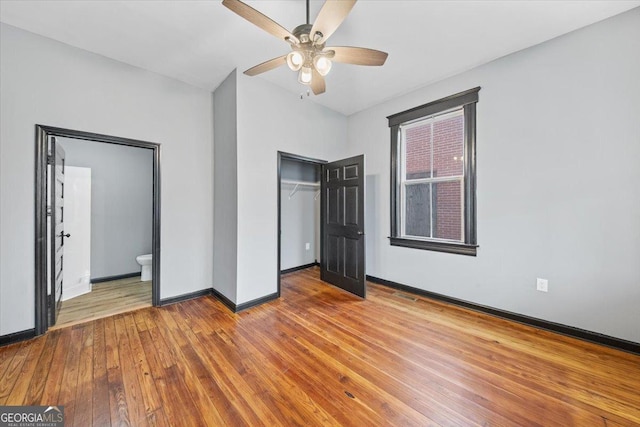 unfurnished bedroom with ceiling fan, wood-type flooring, ensuite bathroom, and a closet