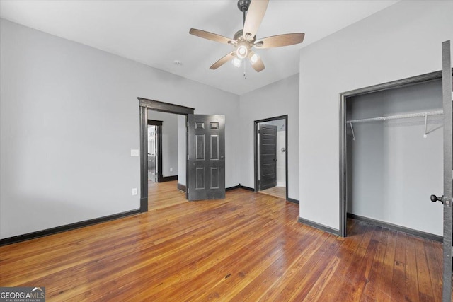 unfurnished bedroom with lofted ceiling, hardwood / wood-style floors, a closet, and ceiling fan