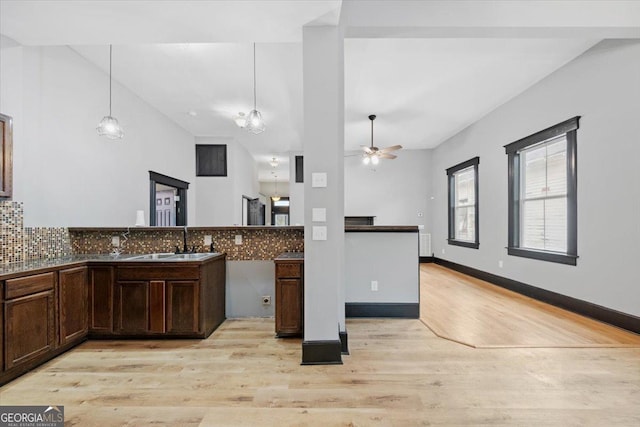 kitchen with sink, hanging light fixtures, light wood-type flooring, ceiling fan, and decorative backsplash