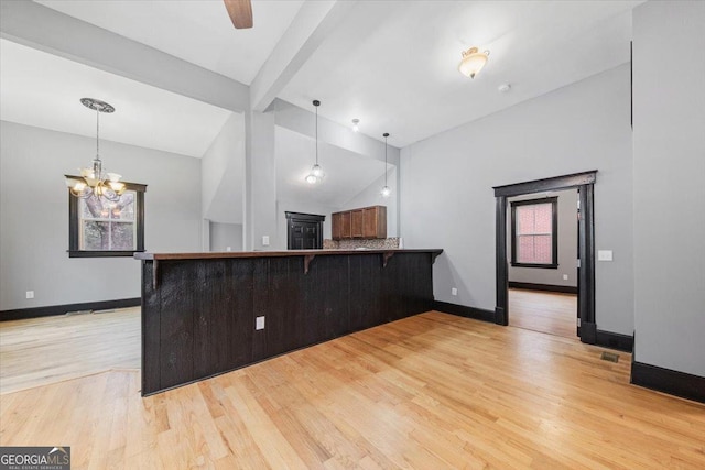 kitchen featuring a kitchen bar, vaulted ceiling with beams, a chandelier, light wood-type flooring, and kitchen peninsula