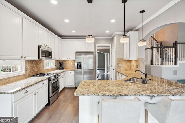 kitchen with appliances with stainless steel finishes, pendant lighting, white cabinetry, and kitchen peninsula