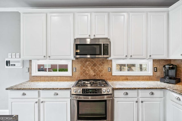 kitchen with white cabinetry, appliances with stainless steel finishes, tasteful backsplash, and light stone counters