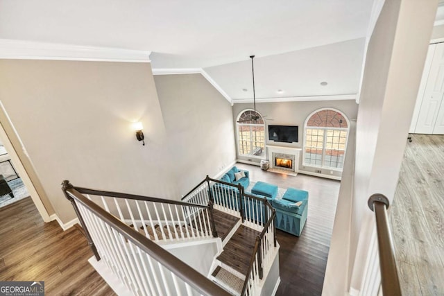 staircase featuring hardwood / wood-style floors, vaulted ceiling, and ornamental molding