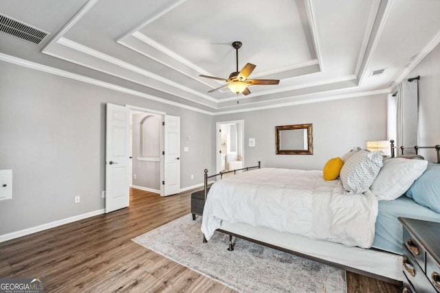 bedroom featuring a raised ceiling, ceiling fan, wood-type flooring, and ornamental molding