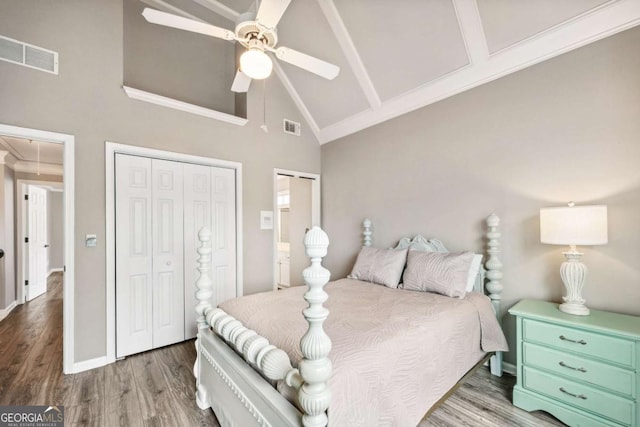 bedroom featuring hardwood / wood-style flooring, high vaulted ceiling, two closets, and ceiling fan