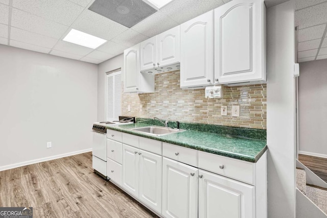 kitchen with sink, light wood-type flooring, white electric stove, white cabinets, and tasteful backsplash