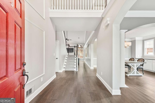 foyer featuring ornate columns, dark wood-type flooring, and ornamental molding