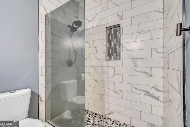 bathroom featuring tiled shower and toilet