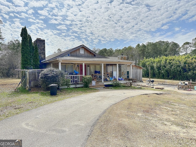 view of front of house with a chimney, a porch, and board and batten siding