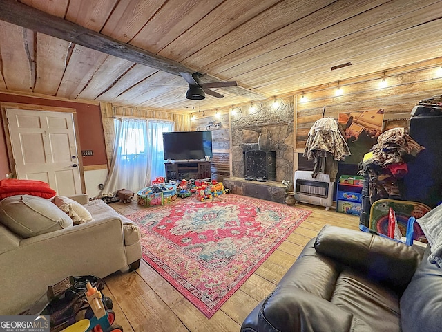 living room with heating unit, wood ceiling, ceiling fan, a stone fireplace, and hardwood / wood-style floors