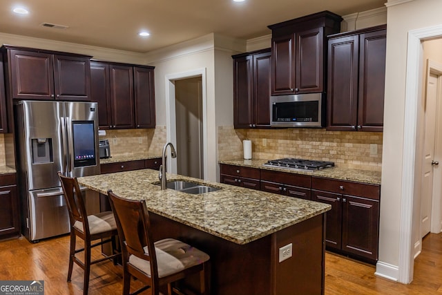 kitchen with a breakfast bar, sink, stainless steel appliances, and an island with sink