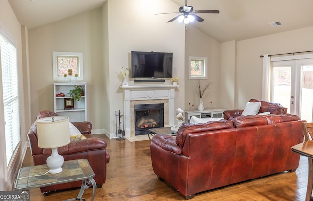 living room with hardwood / wood-style floors, french doors, a tile fireplace, ceiling fan, and high vaulted ceiling