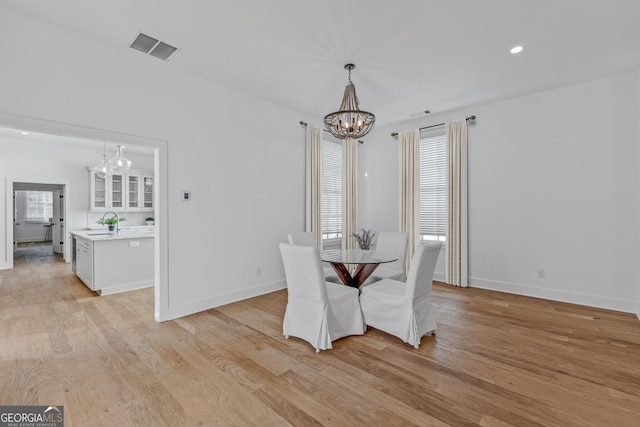 dining area featuring light wood-type flooring, sink, and a chandelier