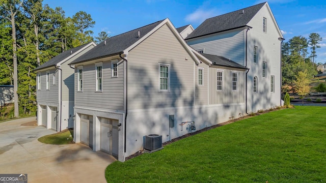 view of side of home featuring concrete driveway, a lawn, a garage, and central AC