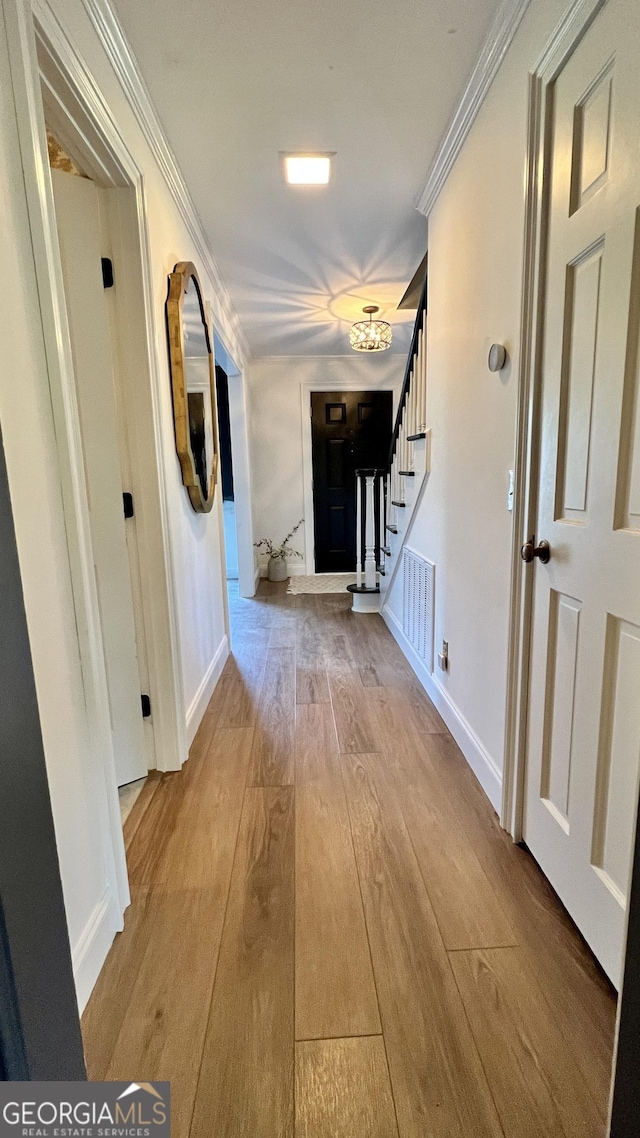 hallway with ornamental molding and light wood-type flooring