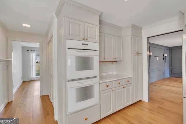 1706 Murphy Ln, Dublin, GA 31021 - kitchen featuring white double oven, light wood-style floors, ornamental molding, and white cabinetry
