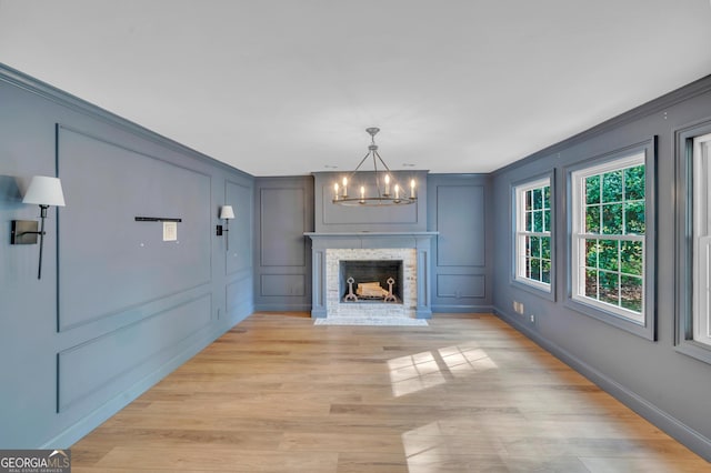 1706 Murphy Ln, Dublin, GA 31021 - unfurnished living room with a decorative wall, a chandelier, crown molding, and light wood-style flooring