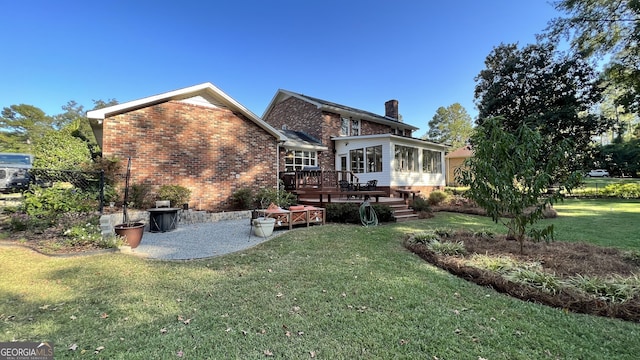 back of property featuring a yard, a sunroom, and a deck