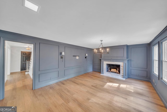 1706 Murphy Ln, Dublin, GA 31021 - unfurnished living room featuring a decorative wall, a chandelier, light wood-style flooring, a fireplace, and crown molding