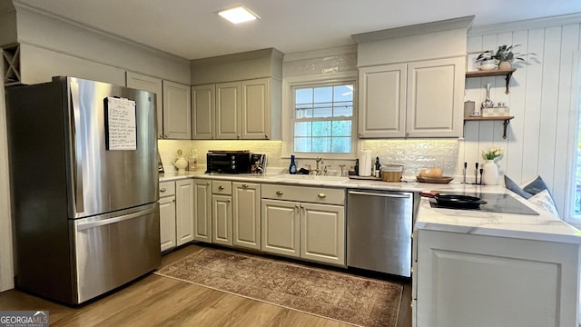 kitchen featuring appliances with stainless steel finishes, hardwood / wood-style floors, sink, backsplash, and ornamental molding