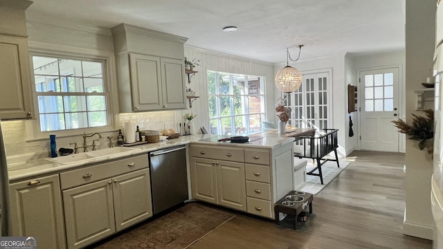 kitchen featuring sink, ornamental molding, dishwasher, kitchen peninsula, and pendant lighting