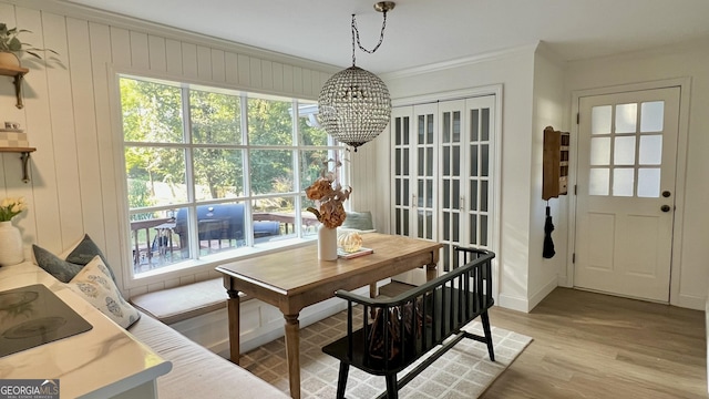 dining area featuring an inviting chandelier, crown molding, light hardwood / wood-style flooring, and plenty of natural light