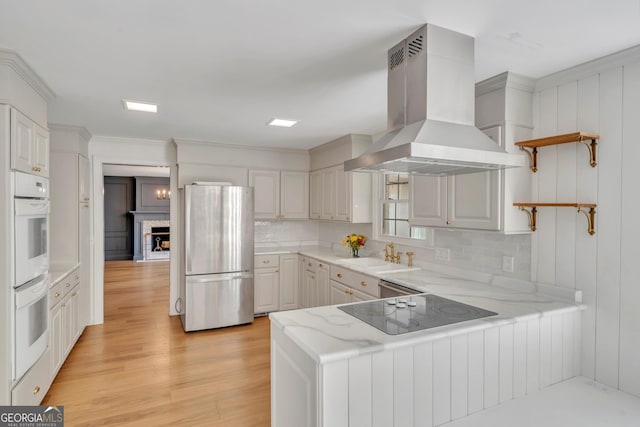 1706 Murphy Ln, Dublin, GA 31021 - kitchen with freestanding refrigerator, wall chimney range hood, black electric cooktop, open shelves, and a peninsula