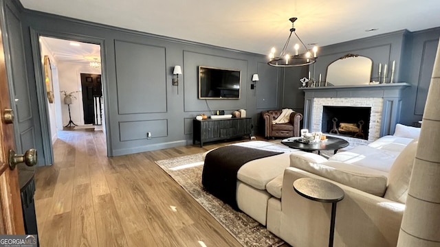 living room with light wood-type flooring, a notable chandelier, and a fireplace