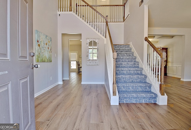 entryway with a high ceiling, stairway, wood finished floors, and baseboards