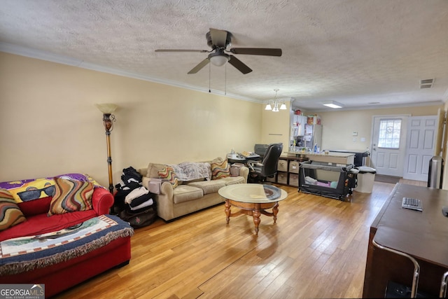 living room featuring visible vents, hardwood / wood-style flooring, ceiling fan, ornamental molding, and a textured ceiling