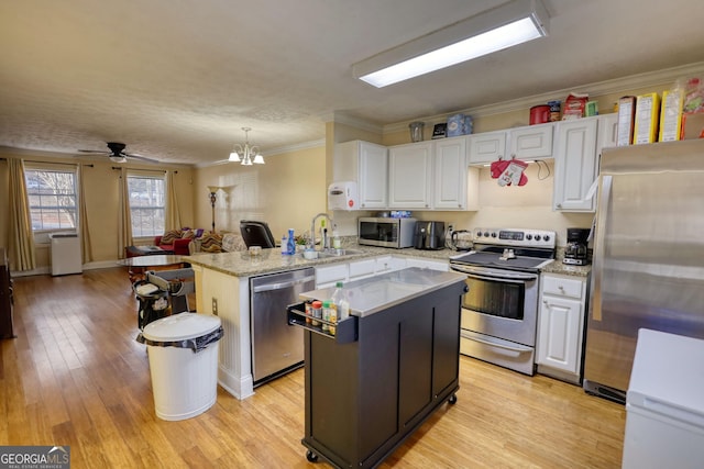 kitchen featuring appliances with stainless steel finishes, white cabinets, a sink, a kitchen island, and a peninsula