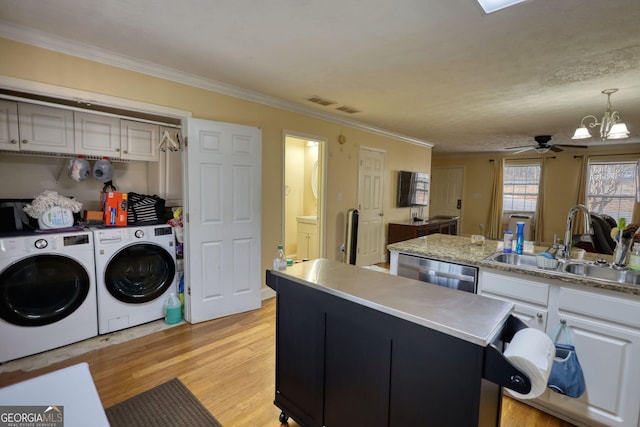 kitchen featuring dishwasher, independent washer and dryer, light countertops, light wood-type flooring, and a sink