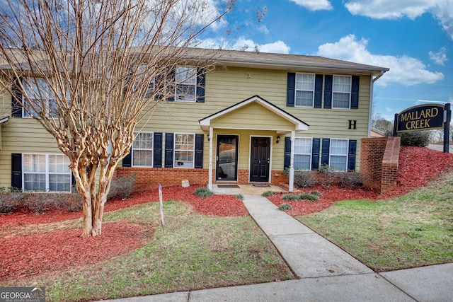 view of front of house with brick siding and a front lawn