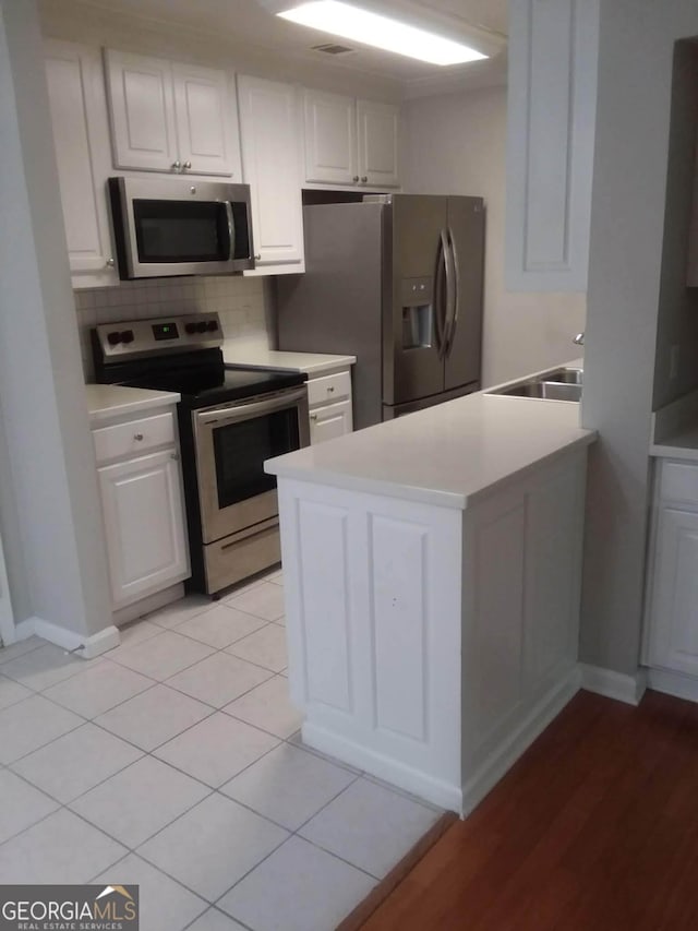 kitchen with white cabinetry, sink, decorative backsplash, light tile patterned floors, and stainless steel appliances