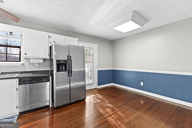 kitchen with dark wood-type flooring, appliances with stainless steel finishes, a textured ceiling, and white cabinets