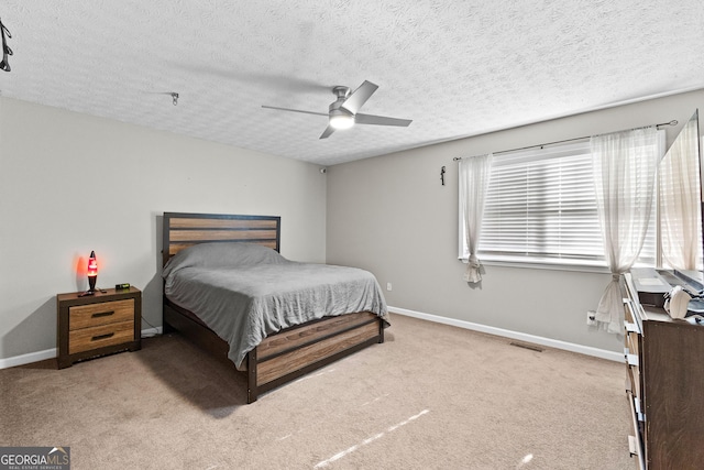 bedroom with ceiling fan, light colored carpet, and a textured ceiling