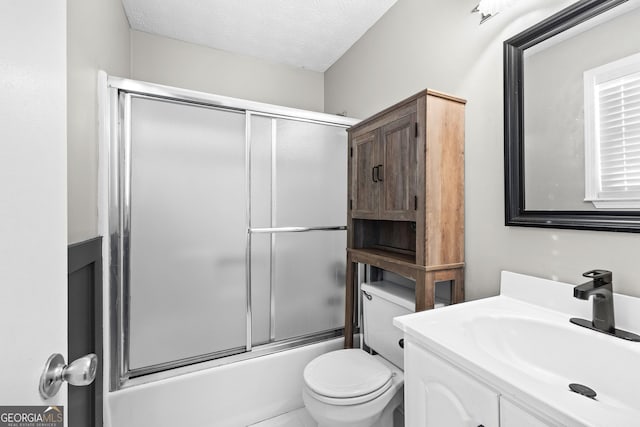 full bathroom featuring vanity, a textured ceiling, combined bath / shower with glass door, and toilet