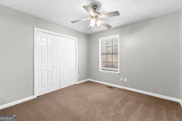 unfurnished bedroom featuring ceiling fan, carpet, a textured ceiling, and a closet