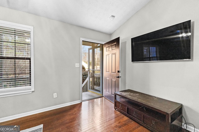 entrance foyer featuring lofted ceiling, wood-type flooring, and a textured ceiling