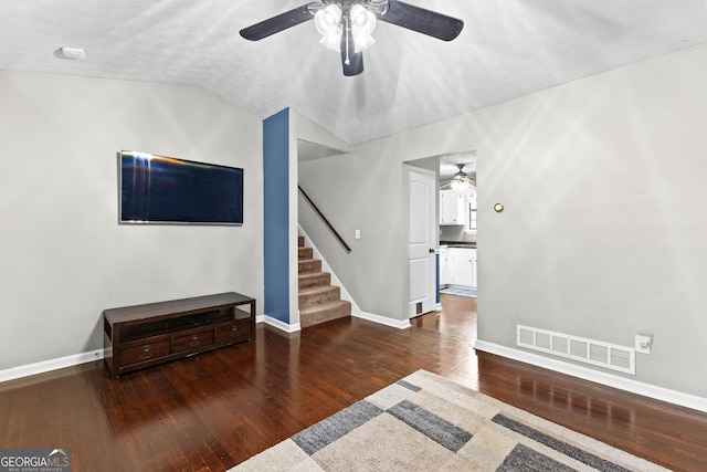 living room featuring dark wood-type flooring, ceiling fan, lofted ceiling, and a textured ceiling