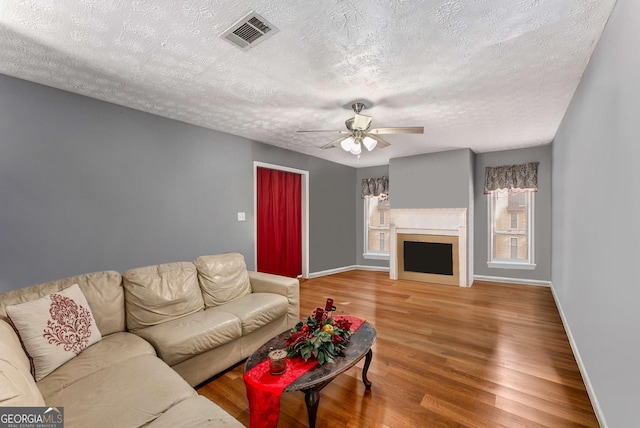 living area with baseboards, a fireplace, visible vents, and wood finished floors