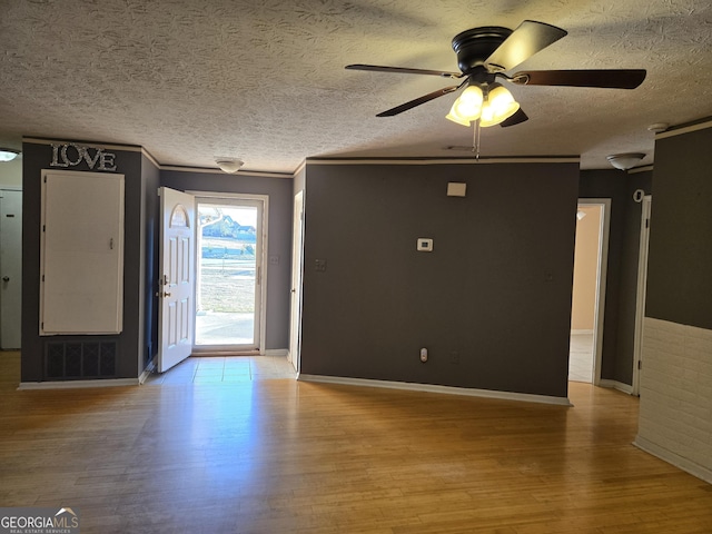 interior space featuring a textured ceiling, ceiling fan, visible vents, light wood-type flooring, and crown molding