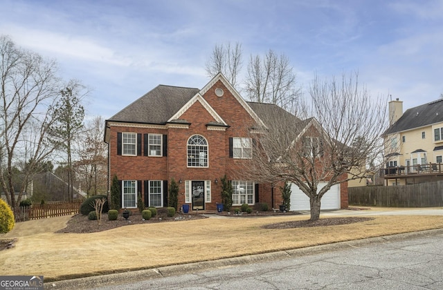 view of front of home with brick siding, fence, driveway, and roof with shingles