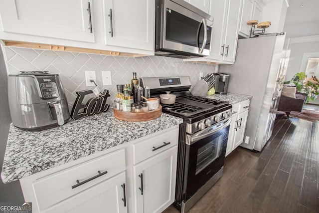 kitchen with dark hardwood / wood-style floors, white cabinetry, backsplash, stainless steel appliances, and light stone countertops