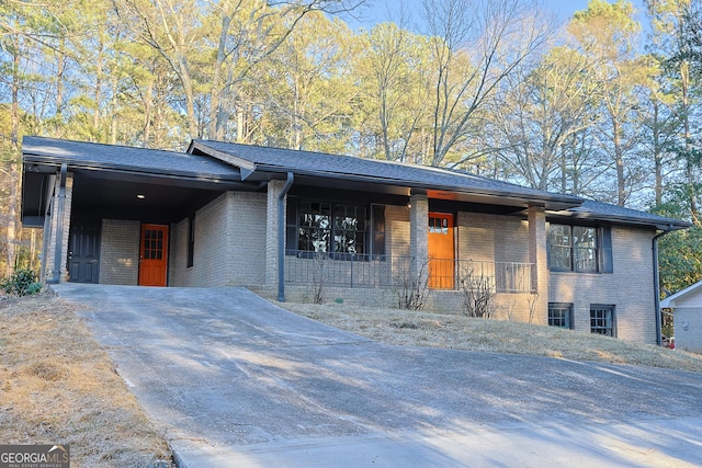 view of front of property with concrete driveway, roof with shingles, covered porch, a carport, and brick siding