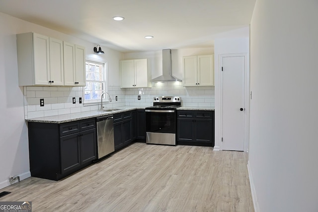 kitchen featuring wall chimney exhaust hood, appliances with stainless steel finishes, light wood-style flooring, and a sink