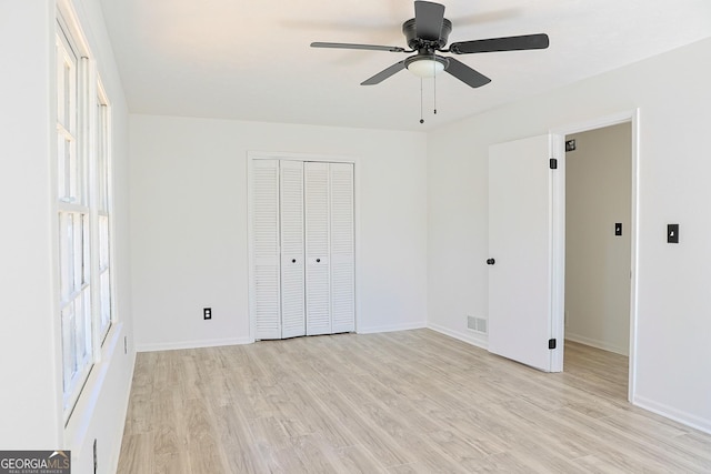 unfurnished bedroom with a closet, visible vents, light wood-style floors, ceiling fan, and baseboards