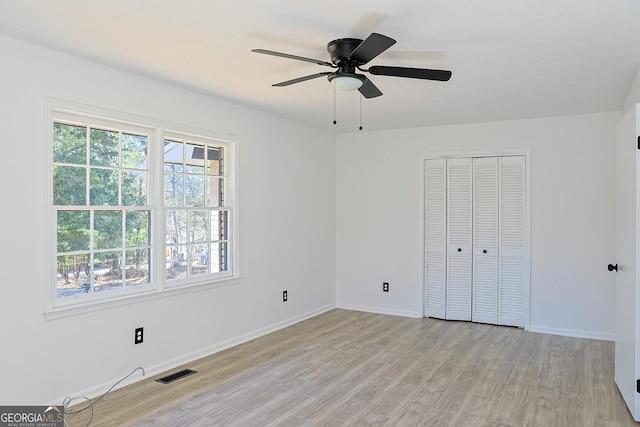 unfurnished bedroom featuring light wood-type flooring, baseboards, multiple windows, and visible vents